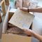 Mitarbeiter verpackt ein kleines Muster in einer Versandbox