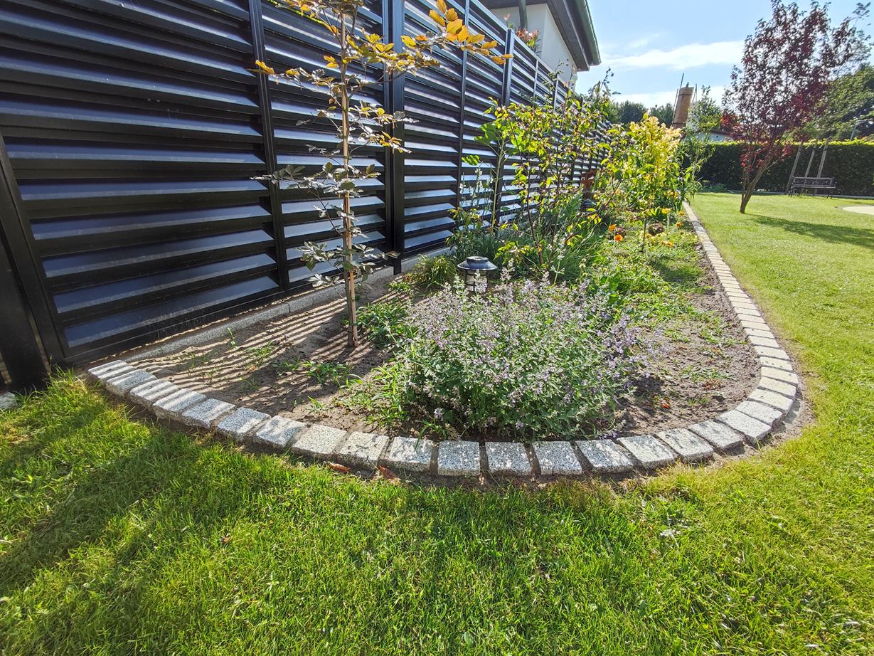 Kundenfoto. Dekorative Beeteinfassung und Abgrenzung zum Rasen Rund angeordnete Pflastersteine als Beeteinfassung