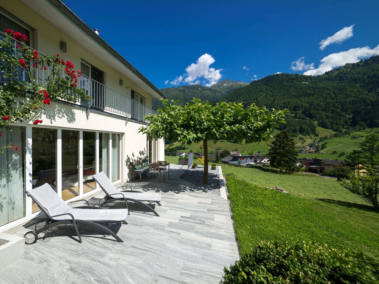 Der moderne Urban Grey Line, hier im Format 40x60cm, fügt sich wunderbar in die Natur ein Terrasse mit Granitplatten, Liegen und Bergen im Hintergrund