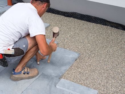 Mann verlegt Blausteinplatten im Edelsplittbett