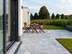 Terrasse mit Marmorplatten Afyon Grey in hellem Grau, Möbeln aus Holz und einem Garten im Hintergrund
