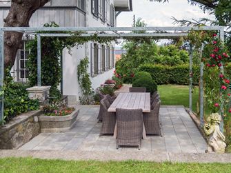Sandsteinplatte Kandla Grey auf einer Terrasse mit Pergola und angrenzendem Rasen