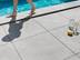 Füsse laufen barfuß auf der Poolumrandung aus Feinsteinzeug-Platten Alpine Grey