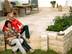 Paar sitzt auf einer Terrasse mit Natursteinplatten aus Travertin Medium SELECT und Natursteinmauer, im Hintergrund Gartenmöbel aus Holz