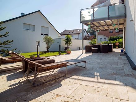 Sonnige Terrasse mit zwei Liegen und Travertin Medium als Bodenbelag