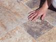 Hand streicht über Travertinplatten Scabas