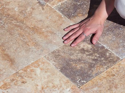 Hand streicht über Travertinplatten Scabas