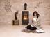 Frau sitzt mit einer Decke und einer Tasse Tee auf Kalksteinfliesen von einem gemütlichen Kamin und einer Natursteinwand