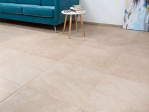 Fliesen in Kalksteinoptik mit türkisfarbener Couch und weißem Beistelltisch