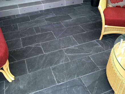 Korbmöbel mit roten Kissen auf dunklen Schieferfliesen Black Rustic mit weißen Fugen