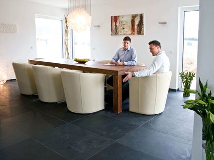 Esstisch mit weißen Sesseln und zwei Menschen auf Schieferfliese Mustang in dunklem Grau