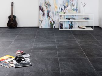 Moderne Fliesen aus Feinsteinzeug in Schieferoptik in einem Wohnzimmer mit modernem Gemälde im Hintergrund und einer Gitarre an der Wand