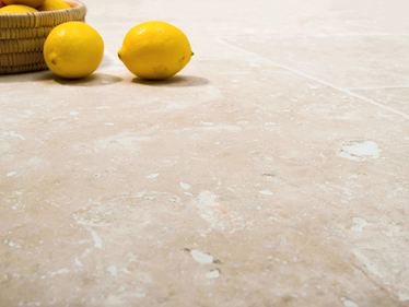 Travertin Ivory Cream in Froschperspektive mit Zitronen