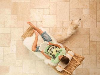 Junge liest im Liegestuhl auf Travertinfliesen Light im Römischen Verband verlegt