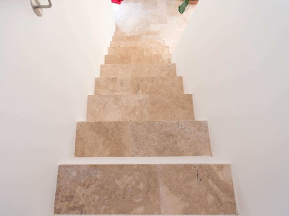 Travertin Medium auf der Treppe. Hier mit Fuge. Treppe mit weissen Wänden und Travertin Medium als Trittplatten