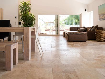 Wohnzimmer mit brauner Couch, weißen Wänden und Travertinfliesen Medium in Braun-Beige als Bodenbelag