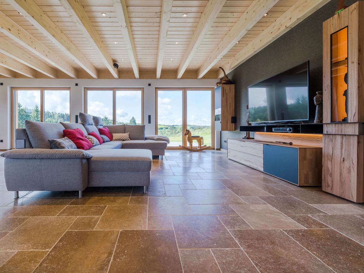 Wohnliches Flair mit nussbraunem Travertin Wohnzimmer mit grauem Sofa und walnussbraunen Travertinfliesen Noce SELECT