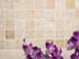 Lila Blüten vor einem beige-braunen Travertin-Mosaik