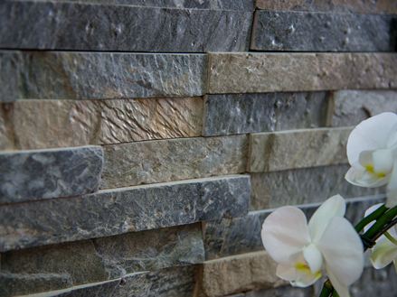Weiße Orchideen neben Wandverblender Quarzit Deoli Green aus einzelnen Riemchen