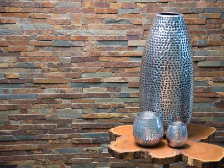 Eine große und zwei kleine Vasen in Silber vor buntem Wandverblender aus Schiefer