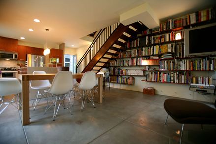 Modernes Wohnzimmer auf Betonboden mit großer Bücherwand im Hintergrund