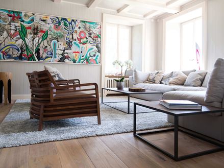 Wohnzimmer mit gemütlicher Couch, Holzboden und modernem Gemälde an der Wand