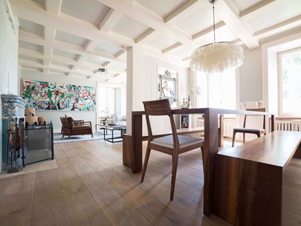 Modernes Wohn- und Esszimmer mit hohen, weißen Decken, Holzboden und einem modernen Gemälde im Hintergrund