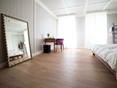 Schlafzimmer mit Holzboden, großen Fenstern und einem Spiegel an der Wand