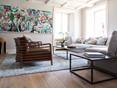 Wohnzimmer mit gemütlicher Couch, Holzboden und modernem Gemälde an der Wand