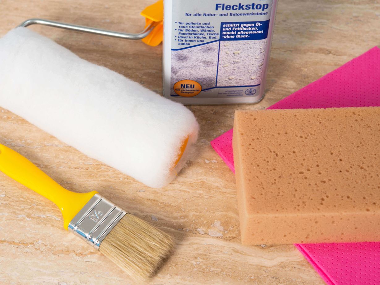 Zubehör zum Imprägnieren liegt auf einer Natursteinfliese in hellem Beige