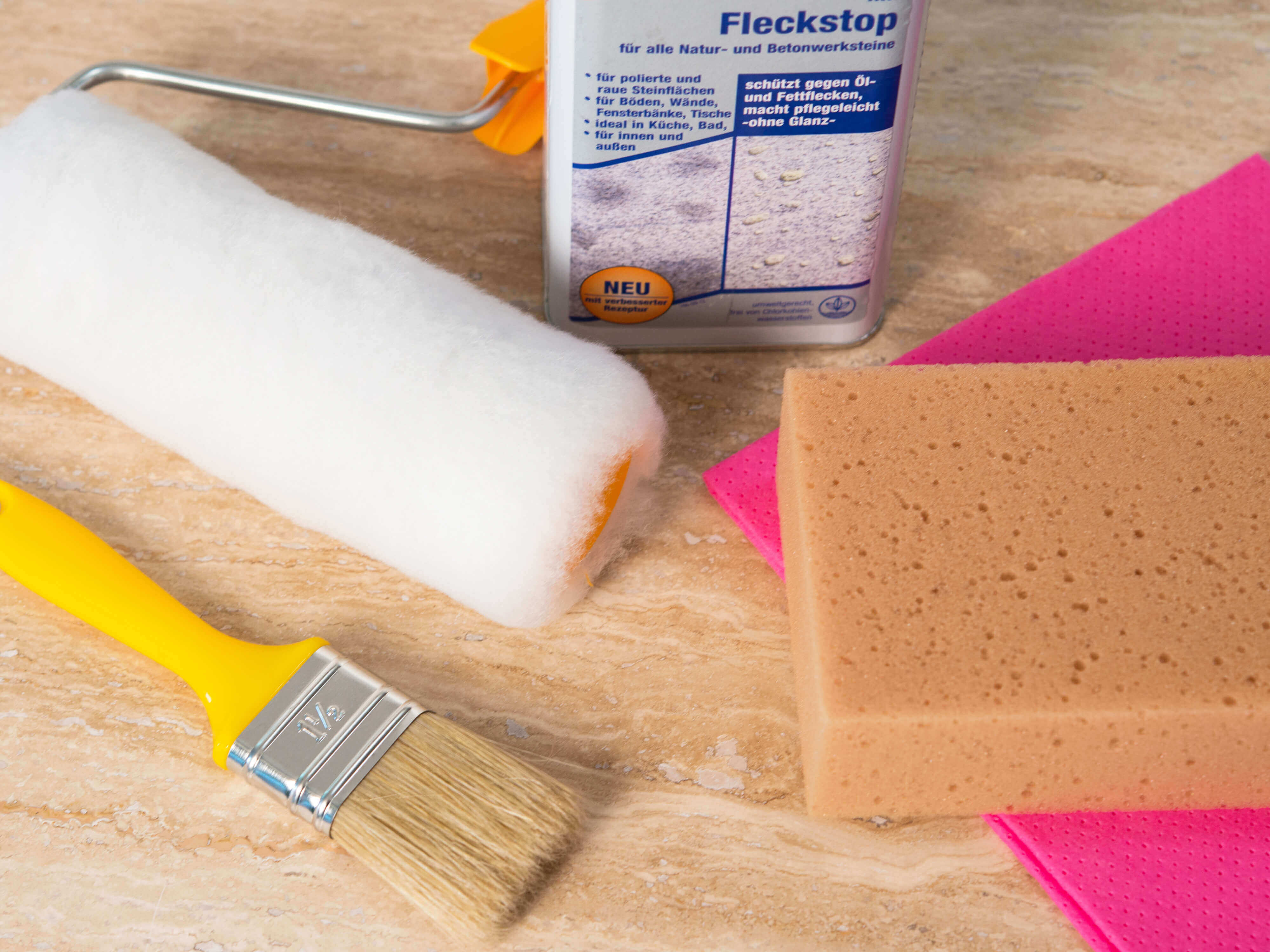 Zubehör zum Imprägnieren liegt auf einer Natursteinfliese in hellem Beige
