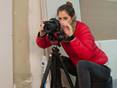 Mitarbeiterin in roter Jacke stellt die Videokamera zum Dreh ein