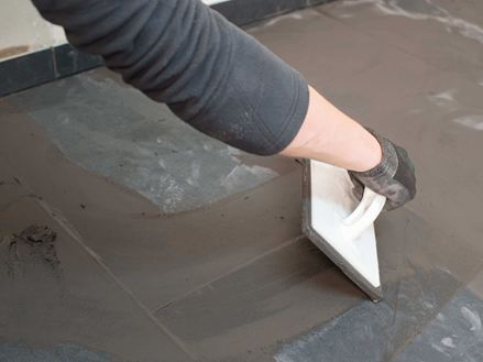 Ein Verleger verfugt Natursteinfliesen aus Schiefer