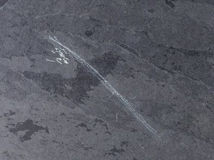 Kratzer in einem dunklen Naturstein