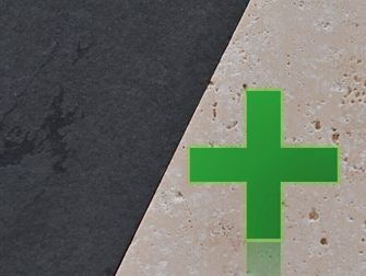 Heller Naturstein neben dunklem Naturstein, darauf ein grünes Kreuz