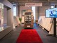 Showroom mit großen Mustertafeln und einem Handmuster-Automat, davor ein roter Teppich