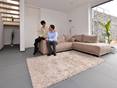 Grossformatige Schieferfliese Grey Slate im Wohnzimmer mit heller Couch und weissen Wänden. Ein Paar sitzt auf der Couch