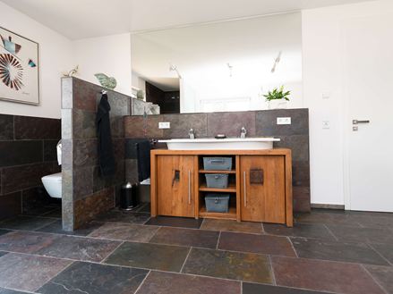 Bad mit Holzmöbeln und Schieferfliese Peacock Multicolor