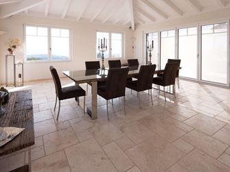 Esszimmer mit hoher Decke, Tisch und Stühlen auf Travertin Light in römischem Verband