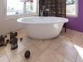 Freistehende Badewanne mit orientalischen Accessoires auf Travertinfliese Light mit getrommelter Oberfläche