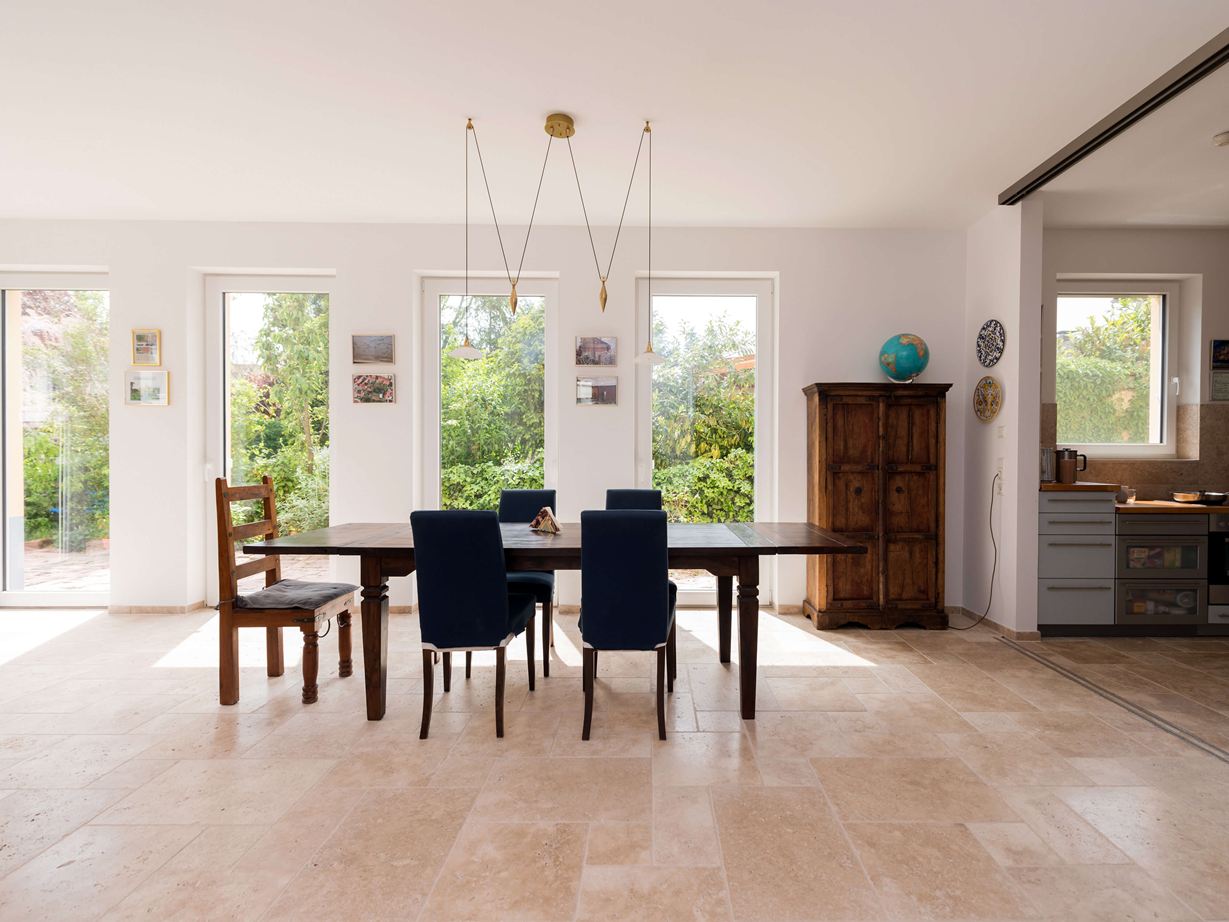 Heller Essbereich mit Holzmöbeln und Travertinfliesen in Beige als Bodenbelag