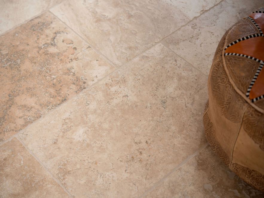 Nahaufnahme von Travertinfliese Rustic mit Sitzkissen im rechten Bildteil
