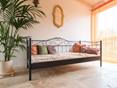 Schlafzimmer mit Bett, Pflanze und Travertin Rustic auf dem Boden