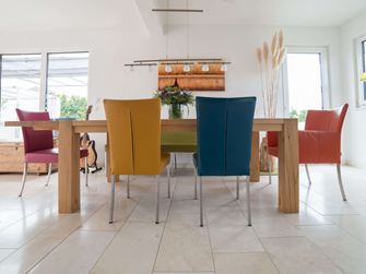 Esstisch aus Holz mit bunten Stühlen auf Travertin Vanilla Rustica