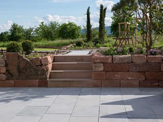 Mediterraner Garten mit Natursteinmauer und Kalksteinplatten Blaustein Azur im Vordergrund