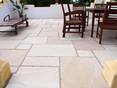 Terrasse mit dunkelbraunem Holztisch, dunkelbraunen Holzstühlen und Sandsteinplatte Yellow Mint als Bodenbelag