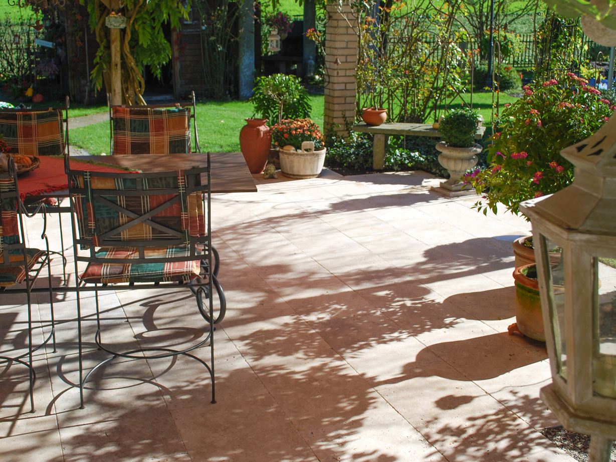 Terrasse mit Gartenstühlen, verschiedenen Blumenkübeln und Rasenfläche im Hintergrund mit Travertinplatte Medium Select