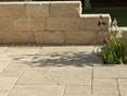 Travertinplatte Medium Select mit Natursteinmauer und Blumen im Hintergrund