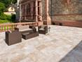 Terrasse mit Gartenmöbeln und Natursteinwand im Hintergrund, Bodenbelag: Travertin Medium mit getrommelter Oberfläche