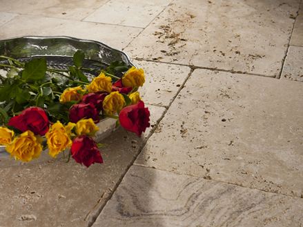 Ein Tablett mit Rosen auf verlegten Travertinplatten in Beige und Braun